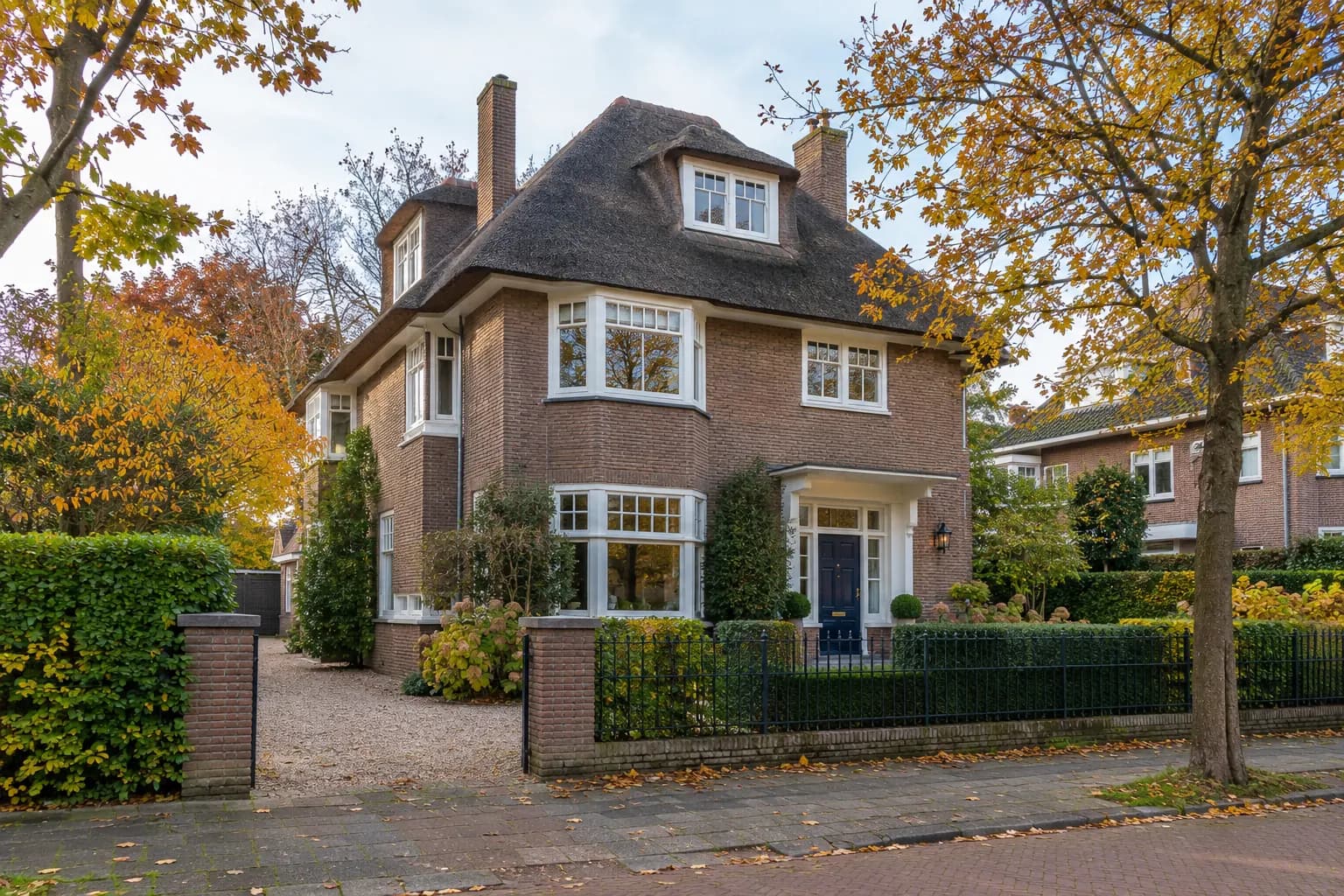 Monumentale huizen met smalle gevels en houten kozijnen langs een vliet in Voorburg, met bomen en een brug op de achtergrond